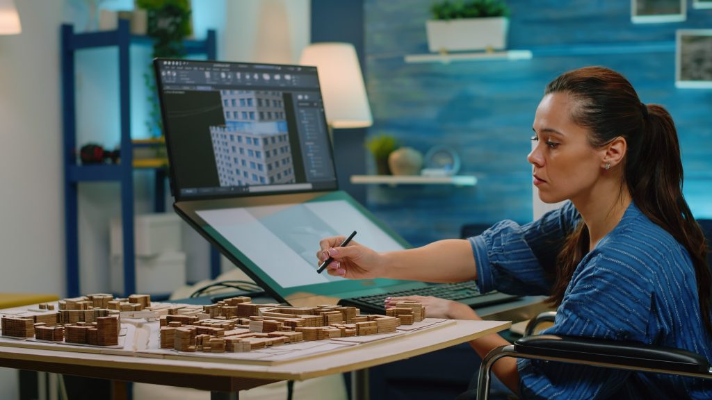 woman-with-disability-using-touch-screen-construction-layout-office-architect-wheelchair-analyzing-building-model-computer-table-creating-blueprint-plan-development-min